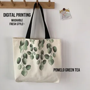 Minimalist cream canvas tote bag with green eucalyptus leaf print and black handles