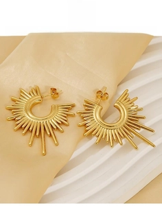 Detailed close-up of golden titanium steel earrings featuring a sunburst geometric design