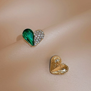 Close-up of heart studs with green gemstone and pavé rhinestones on beige leather