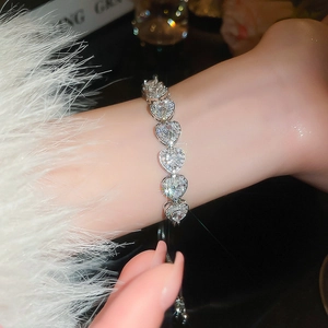 Close-up of heart-shaped silver bracelet with zircon stones on female wrist