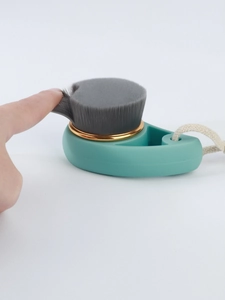 Detail of soft charcoal fiber bristles and green handle with gold ring on facial brush