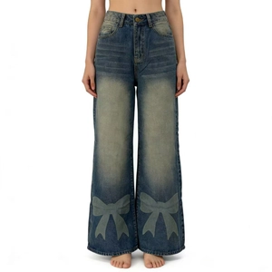 Détail d'un jean large bleu vintage avec imprimé nœud et finition délavée usée