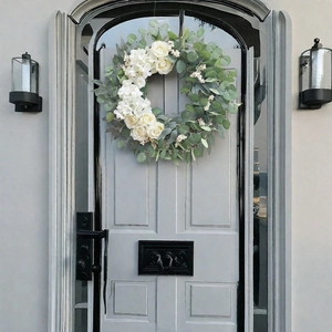 Artificial white rose and eucalyptus wreath hanging on a gray wooden door for home decor
