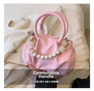 Detail of pink ruched dumpling bag with marble beaded handle and brand logo
