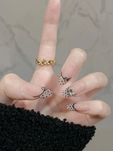 Close-up of French retro dot press-on nails with 3D butterfly charms and gold ring