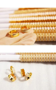Macro detail of gold-plated hoop earrings with brown enamel inlay and clasp closure