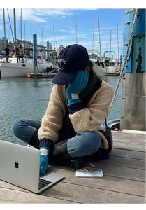 Detail shot of heavy weight blue wool knit gloves with premium brand labels by the pier