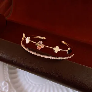 Golden double-layer open bangle featuring zircon clover charms and luxury flower details