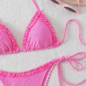 Detail of pink striped bikini with ruffle trim and side-tie bottoms on a soft texture