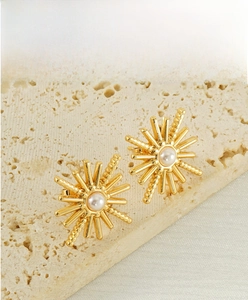 Détail de la boucle d'oreille en acier avec perle et design étoile solaire