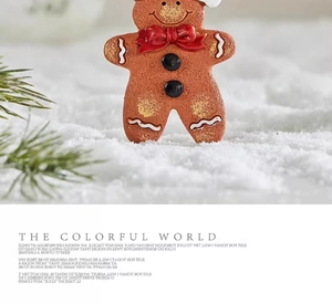 Detailed close-up of a resin gingerbread man ornament with red bow in a snowy setting