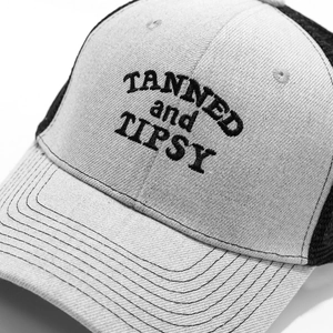 Close-up of 3D embroidery with TANNED and TIPSY text on a mesh baseball cap detail
