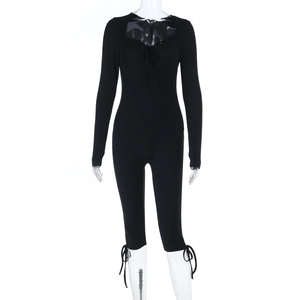 Close-up of black ribbed jumpsuit featuring delicate lace trim and front lace-up detail