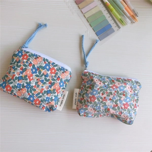 Detail of floral cotton coin purses with zipper and blue lanyards on wooden desk