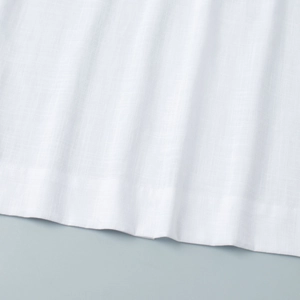 Macro detail of the white cotton-linen fabric texture and hem of the sleeveless dress