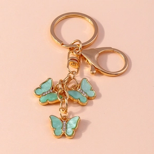 Detail of three mint green butterfly pendants with white rhinestones on a gold keychain