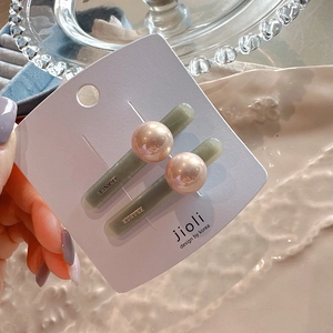 Close-up of elegant pearl hair clips with resin base and FRANCE engraving on card