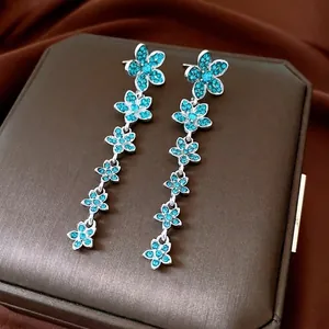 Vintage silver flower drop earrings with blue cubic zirconia on a premium leather case
