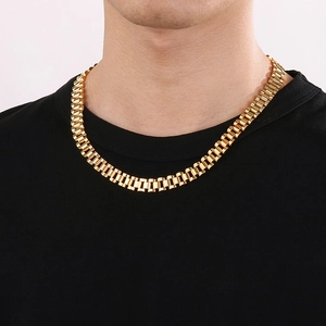 Close-up of a gold-toned watch strap chain necklace worn by a male model on black t-shirt