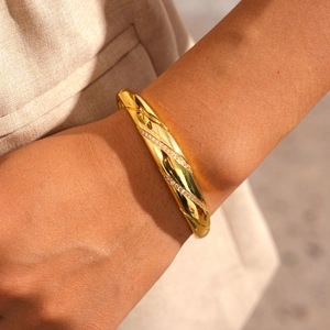 Detail of 18k gold plated twisted bangle with zircon stones on a female wrist