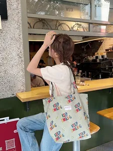 Light green corduroy tote bag with Keep Smiling print shown on a model in a cafe