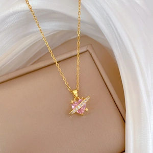 Close-up of golden necklace with a pink heart pendant and sparkling crystal orbit