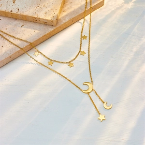 Double-layered gold titanium necklace with star and moon charms on a stone surface