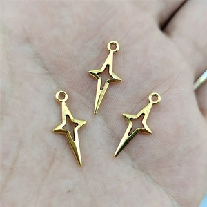 Close-up of three gold hollow cross charms held in hand for DIY jewelry making