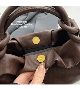 Dettaglio della chiusura magnetica dorata su una borsa a tracolla in pelle marrone