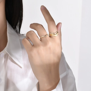 Close-up of gold V-shaped titanium rings with zircons worn on hand for a layered look