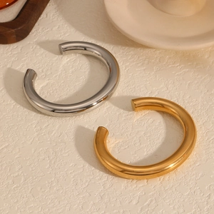 Detailed view of polished gold and silver hollow open bangles on stone base