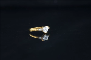 Macro view of a gold heart-shaped moissanite ring with baguette side stones on a black surface