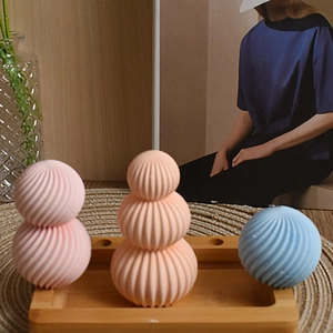 Three textured sphere candles in pink orange and blue on a wooden tray with decor