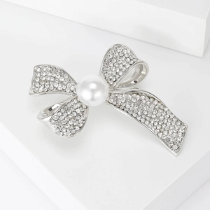 Detailed view of silver bow brooch with pavé rhinestones and a central white pearl