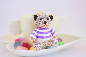 Detailed shot of a crystal teddy bear keychain with purple stripes on a ceramic plate