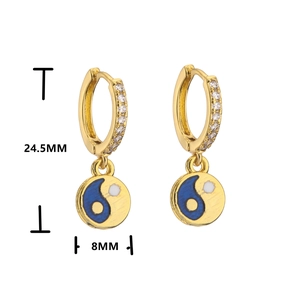 Detail of gold huggie earrings with zircon paving and blue yin yang enamel charms