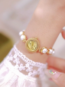 Elegant gold quartz watch featuring a pearl bracelet strap worn on a woman's wrist