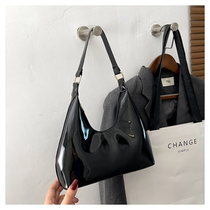 Detail of glossy black patent leather baguette bag with silver metal ring and sleek strap