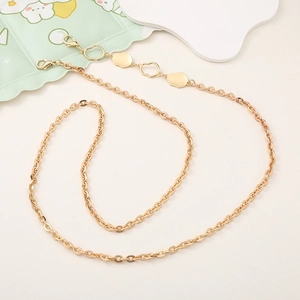 Detailed macro of golden metal accessory chain with lobster clasps and flat decorative charms