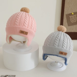 Winter knitted baby hat with pom-poms and ear flaps in pink and grey cable knit