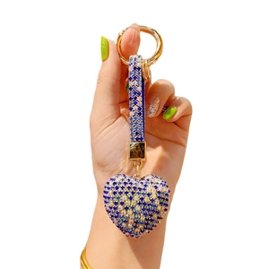 Handheld view of a blue rhinestone heart keychain with gold metal ring and tassel