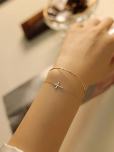 Detail of 18K gold-plated S925 silver cross bracelet with cubic zirconia set on a wrist