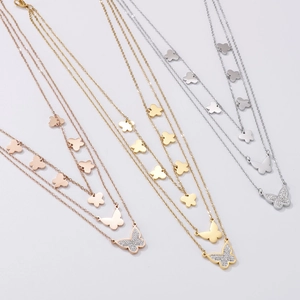 Detail of layered stainless steel butterfly necklaces in rose gold, gold, and silver finishes