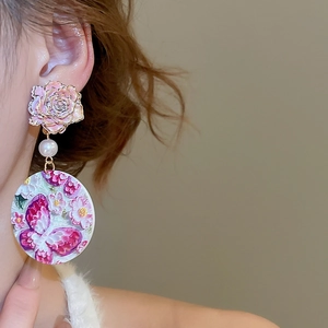 Close-up of earrings featuring pink rose studs, imitation pearls, and butterfly pendants