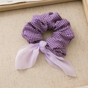 Close-up of purple plaid fabric scrunchie with soft lavender chiffon ribbons on linen
