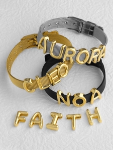 Detailed macro view of customizable mesh band bracelets with gold sliding letters