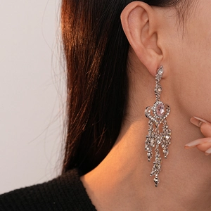 Orecchini a cuore d'argento con strass rosa e frange su modella con luce calda laterale
