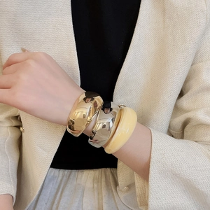 Vue détaillée d'un ensemble de bracelets larges en or, argent et résine sur un mannequin