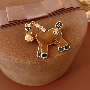 Detailed close-up of brown enamel horse brooch with rhinestone mane and golden snowflake