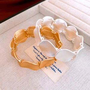 Detail of matte gold and silver oval link bracelets with a fine brushed metal texture
